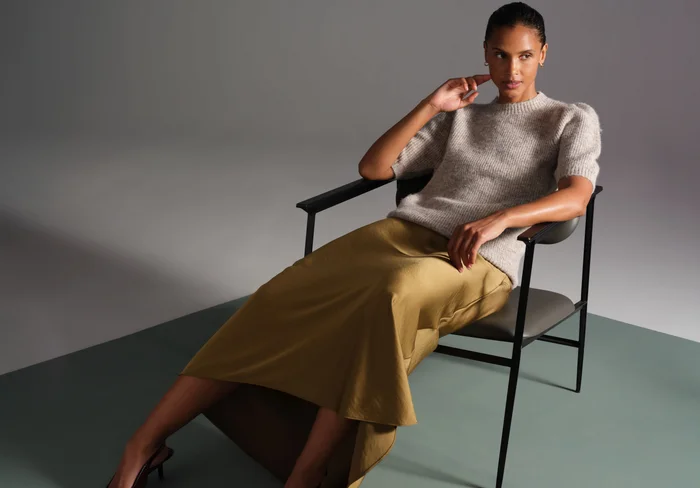 Woman wearing a midi skirt and knitted top.