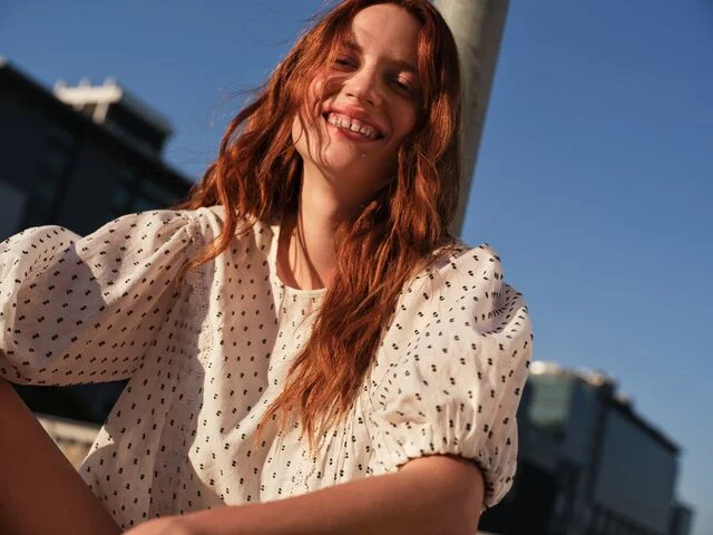 One woman wearing a navy and white striped co ord with a shirt and matching wide leg trousers, holding a beige handbag. Another woman wearing a beige pinstripe co ord with a short sleeved top and wide leg trousers.