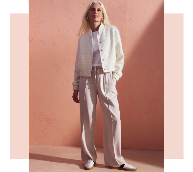 Woman wearing beige wide leg joggers with a white bomber jacket and t shirt